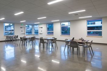 A room with tables and chairs and windows.